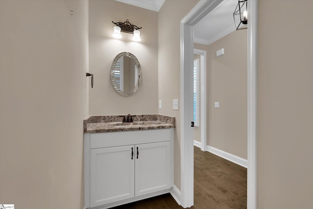 bathroom with baseboards, wood finished floors, ornamental molding, and vanity