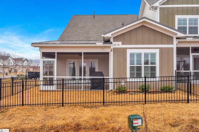 back of property with board and batten siding, roof with shingles, a fenced backyard, and a sunroom