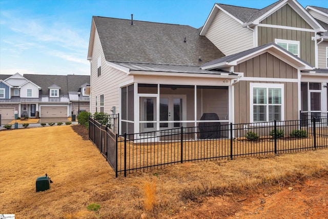 rear view of property featuring board and batten siding, fence, french doors, a sunroom, and a patio