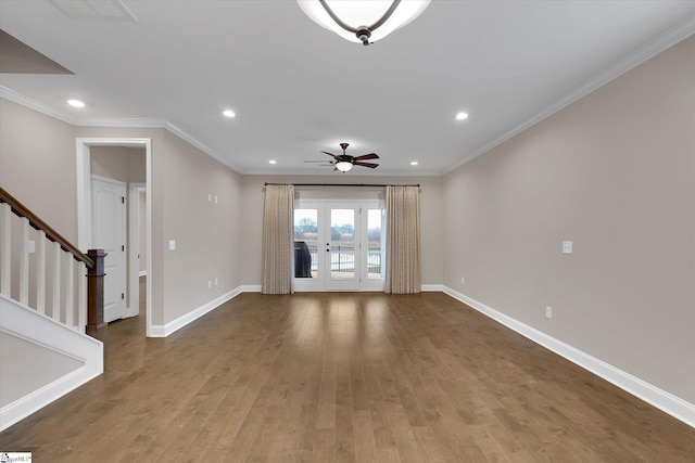 empty room featuring stairway, baseboards, wood finished floors, and ornamental molding