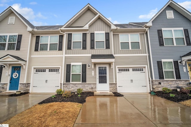 multi unit property with stone siding, driveway, an attached garage, and board and batten siding