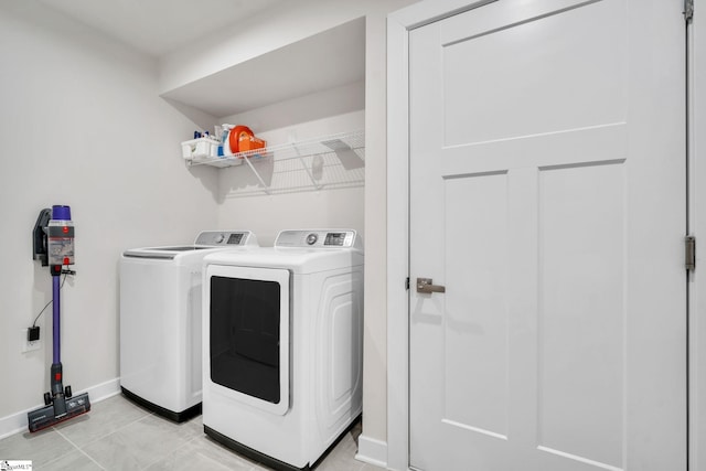 laundry room featuring laundry area, light tile patterned floors, washing machine and dryer, and baseboards