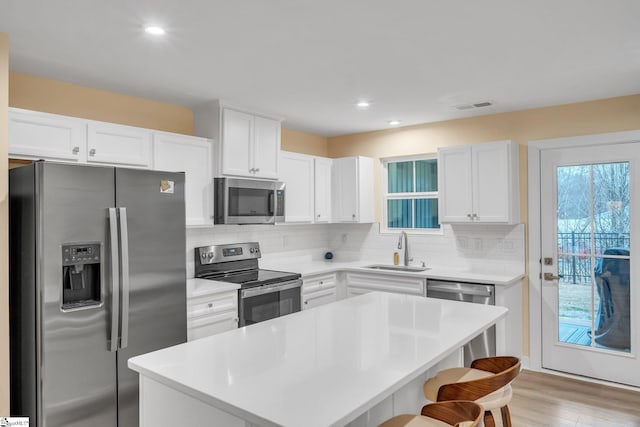 kitchen featuring visible vents, a breakfast bar, a sink, decorative backsplash, and stainless steel appliances