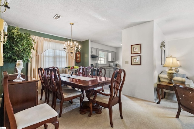 dining space featuring an inviting chandelier, light colored carpet, visible vents, and a textured ceiling