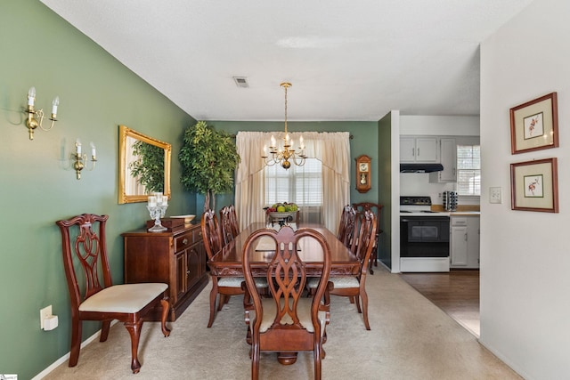 dining area with an inviting chandelier, light colored carpet, visible vents, and baseboards