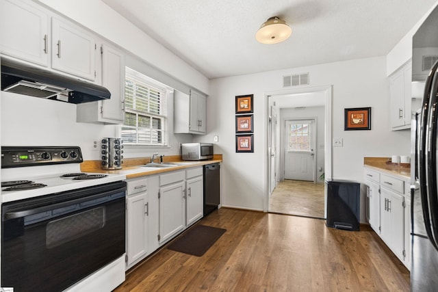 kitchen featuring dark wood-style floors, visible vents, black appliances, light countertops, and under cabinet range hood