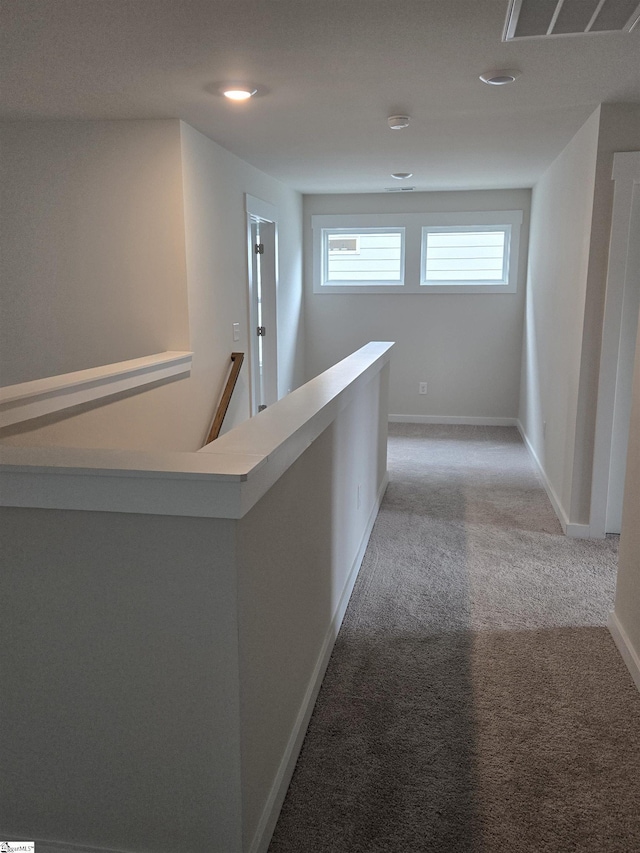 corridor featuring an upstairs landing, baseboards, visible vents, and light carpet