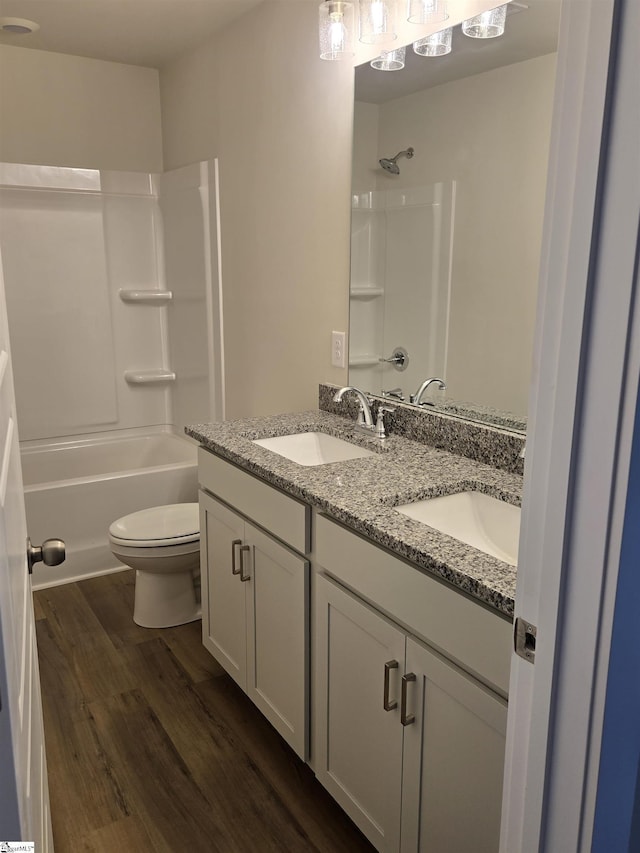 bathroom featuring double vanity, toilet, wood finished floors, and a sink