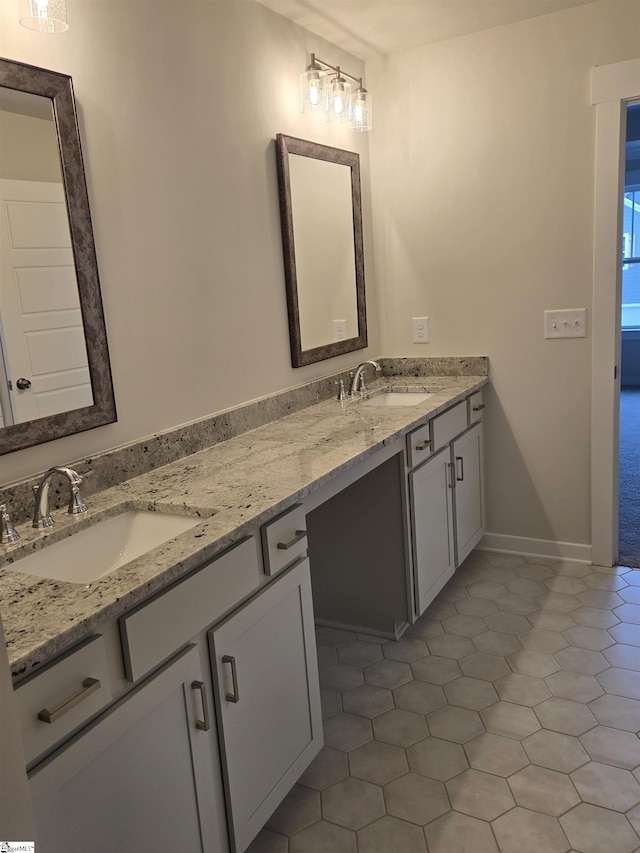 bathroom featuring double vanity, baseboards, and a sink