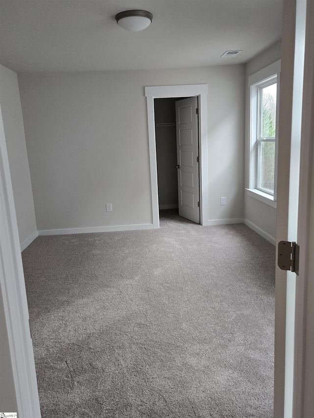 carpeted empty room with visible vents and baseboards