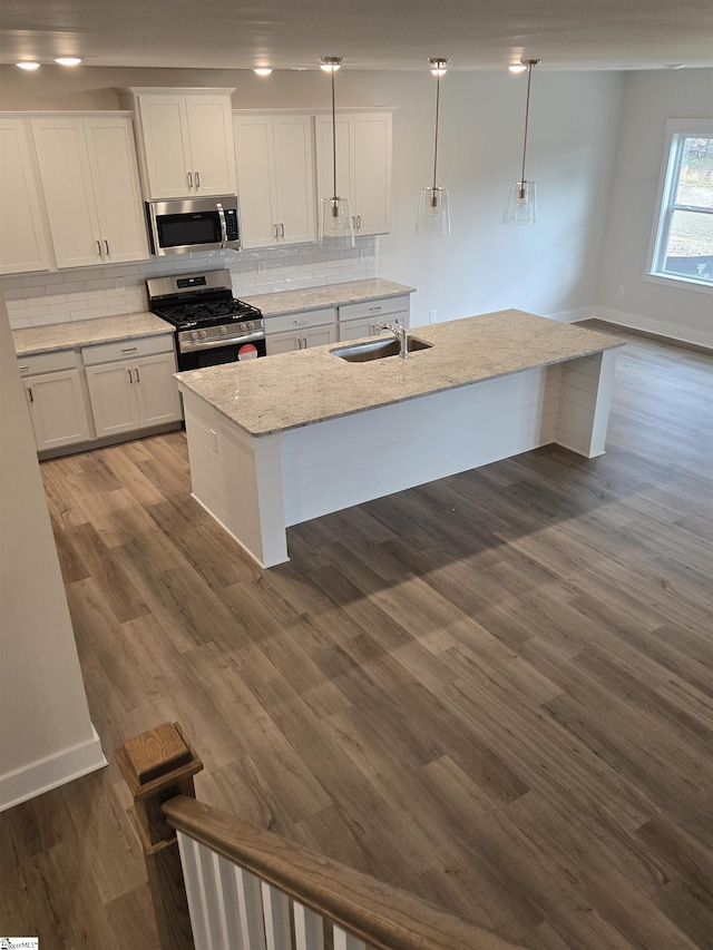 kitchen with dark wood-style floors, a sink, stainless steel appliances, white cabinetry, and backsplash