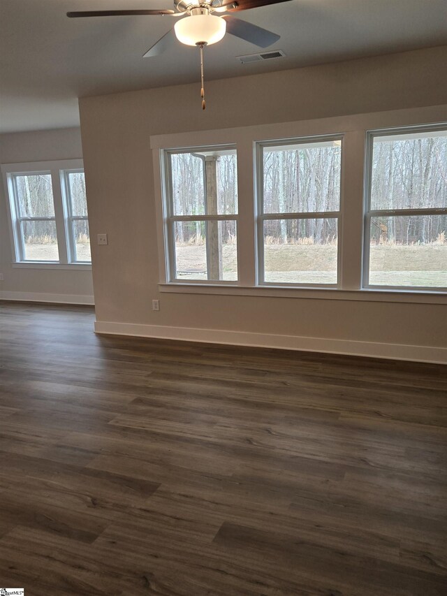 unfurnished room with visible vents, baseboards, dark wood finished floors, and a ceiling fan