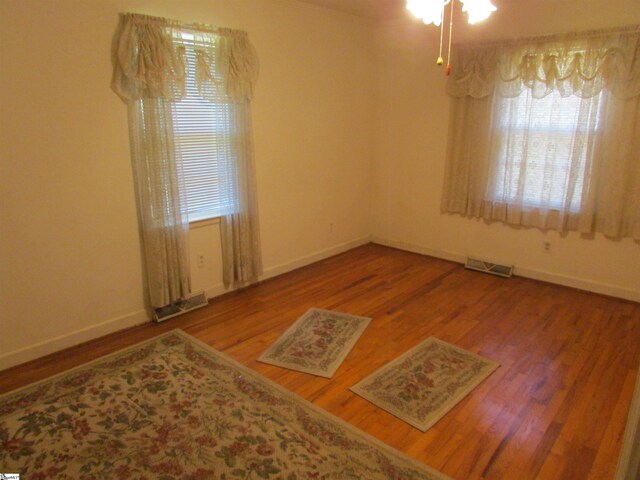 spare room with visible vents, baseboards, and wood finished floors