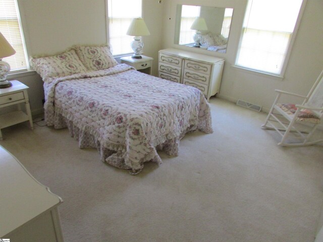 bedroom featuring multiple windows, light colored carpet, and visible vents