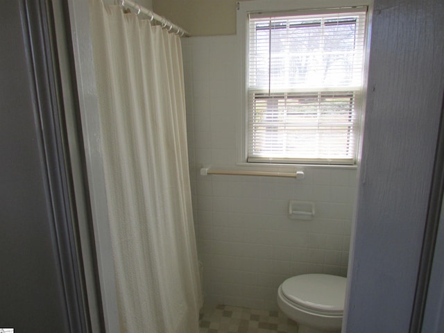 full bath featuring a shower with curtain, toilet, and tile walls