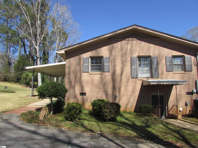 view of home's exterior with brick siding, crawl space, and a yard