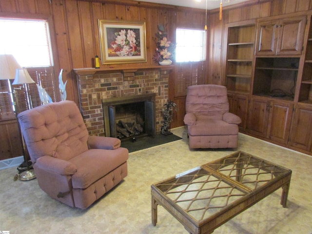 living area with visible vents, wood walls, a brick fireplace, and carpet floors