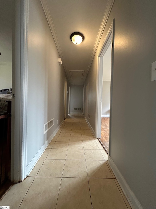 hall featuring light tile patterned floors, visible vents, baseboards, and ornamental molding