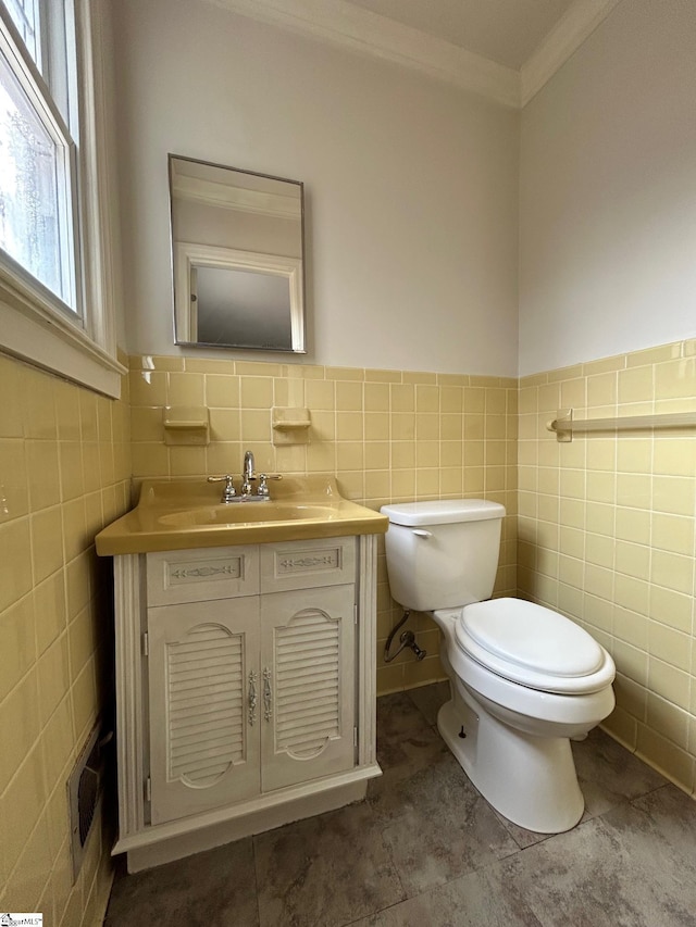 half bathroom with vanity, tile walls, toilet, and ornamental molding