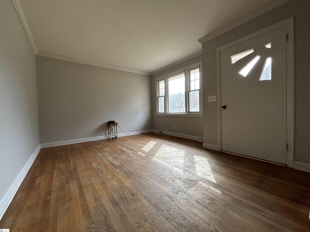 foyer entrance with crown molding, baseboards, and wood finished floors