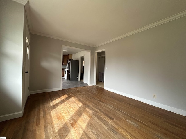 spare room with crown molding, baseboards, and wood finished floors