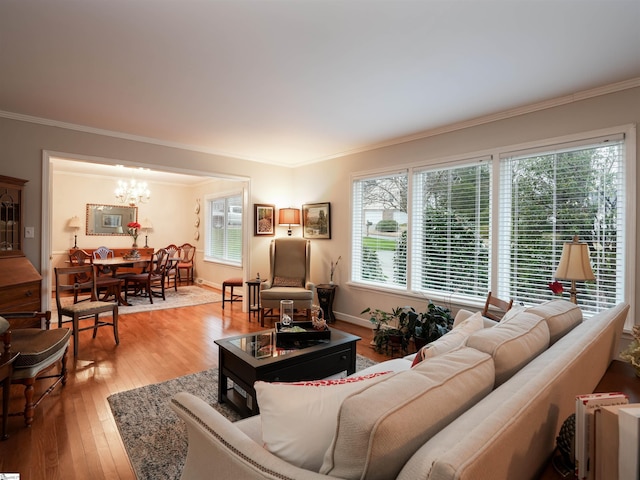 living area featuring a chandelier, baseboards, wood-type flooring, and ornamental molding