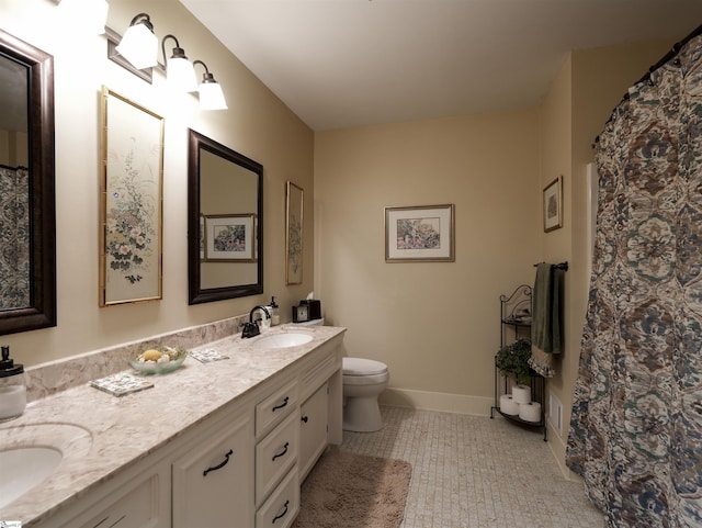 full bath with double vanity, toilet, baseboards, and a sink