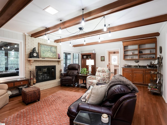 living room featuring beam ceiling, a brick fireplace, and dark wood-style flooring