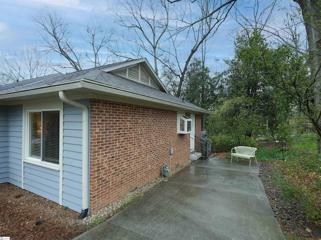 view of side of property with brick siding and roof with shingles