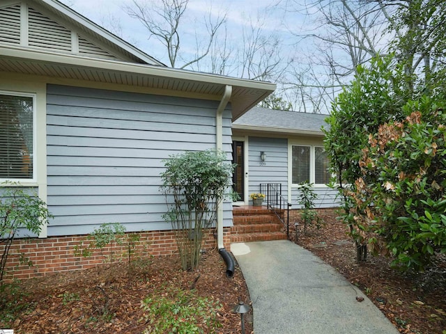 entrance to property featuring roof with shingles