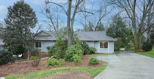 ranch-style house featuring roof with shingles and driveway