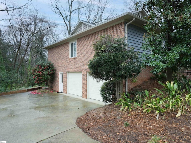 view of side of property featuring brick siding, concrete driveway, and an attached garage