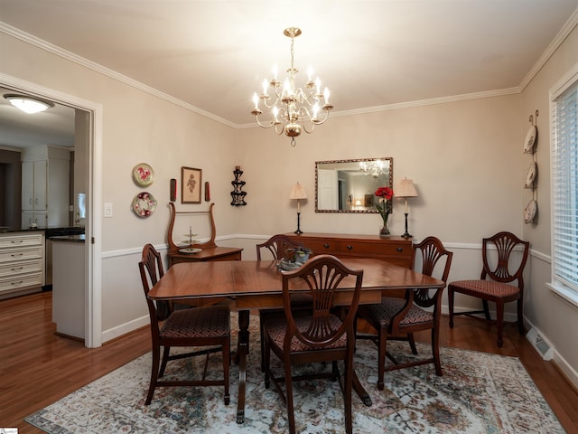 dining room featuring wood finished floors, baseboards, visible vents, ornamental molding, and a notable chandelier