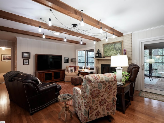 living area with beamed ceiling, ornamental molding, a fireplace, and wood finished floors