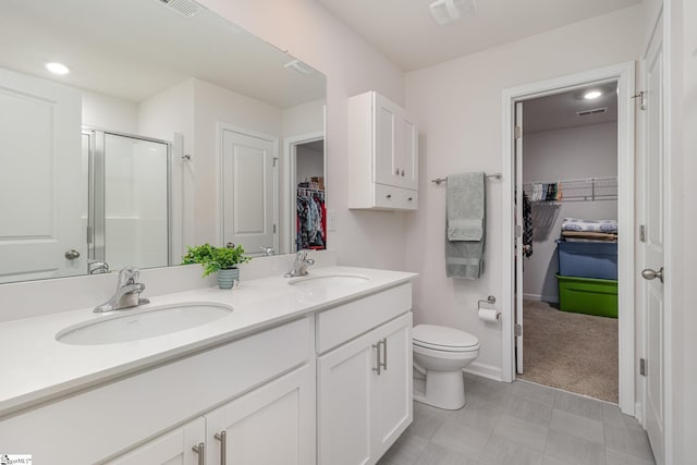 bathroom featuring double vanity, a shower stall, a walk in closet, and a sink