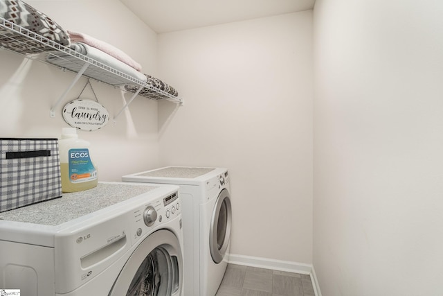 clothes washing area featuring baseboards, laundry area, and washer and clothes dryer