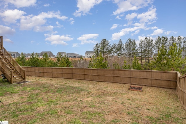 view of yard featuring a residential view, a fenced backyard, and stairs