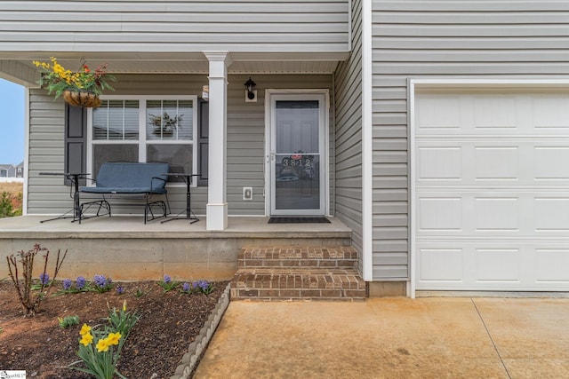 view of exterior entry featuring covered porch and a garage