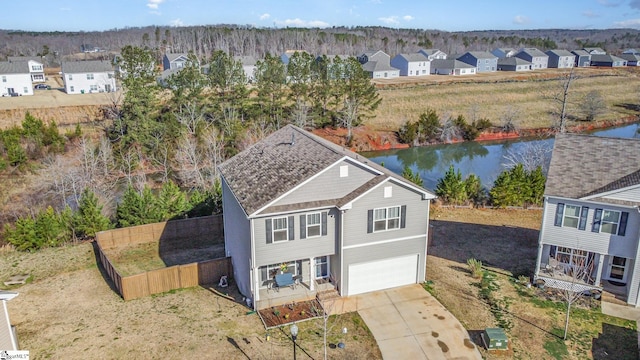 view of front of home featuring fence, driveway, an attached garage, a water view, and a residential view