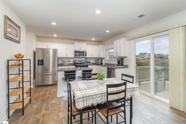 kitchen with light wood-type flooring, visible vents, a sink, white cabinetry, and stainless steel appliances