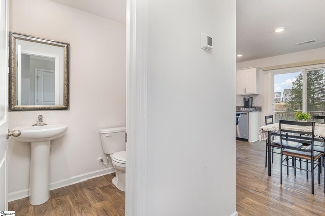 half bath featuring visible vents, baseboards, toilet, recessed lighting, and wood finished floors