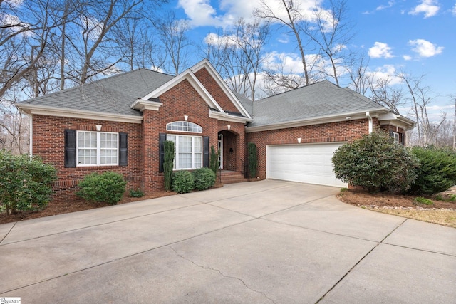 view of front of house featuring brick siding, an attached garage, driveway, and roof with shingles