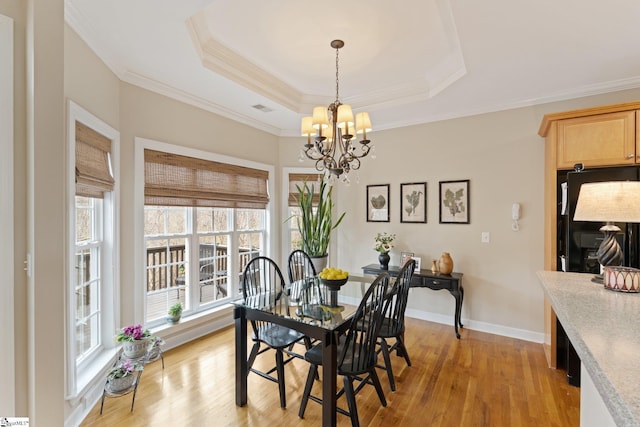 dining space with light wood finished floors, visible vents, an inviting chandelier, and a tray ceiling