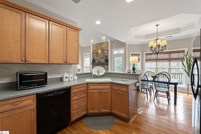 kitchen with a peninsula, black dishwasher, wood finished floors, and a wealth of natural light