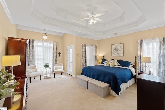 bedroom featuring a tray ceiling, multiple windows, light colored carpet, and ornamental molding