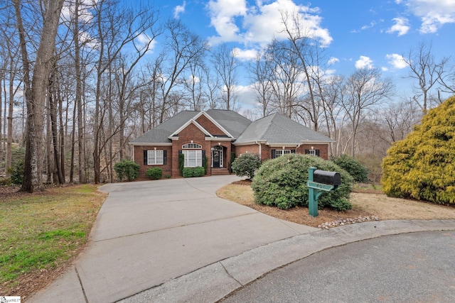 view of front of home featuring concrete driveway, brick siding, and roof with shingles