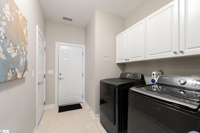 washroom featuring visible vents, baseboards, washer and clothes dryer, light tile patterned floors, and cabinet space