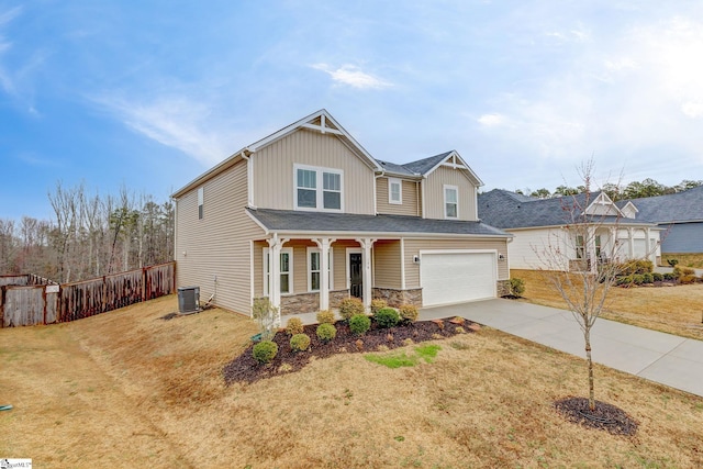 craftsman inspired home with a front yard, fence, driveway, an attached garage, and stone siding