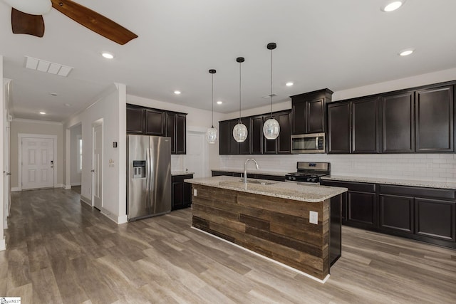 kitchen featuring a sink, tasteful backsplash, appliances with stainless steel finishes, and wood finished floors