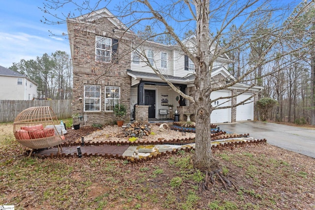 traditional-style home with driveway, fence, covered porch, a garage, and brick siding